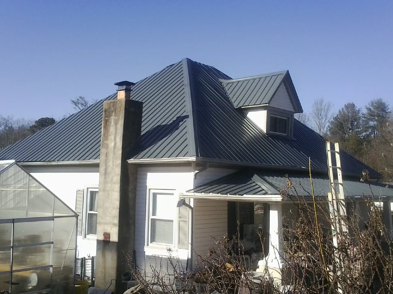 Dark blue standing seam metal roof on a white farmhouse with dormer — Slate & Tile Roof Repair by Roofing Brothers in Hermitage