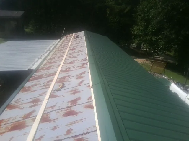 Old rusted panels beside newly installed green metal roofing — Wind Damage Roof Repair by Roofing Brothers in Hermitage
