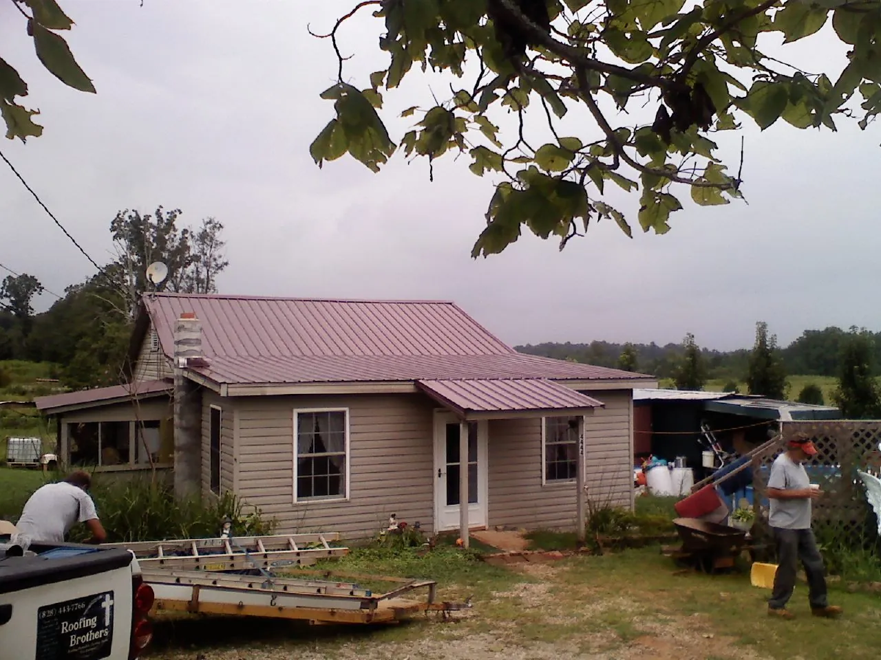 Crew finishing a mauve metal roof on a small farmhouse in Hermitage