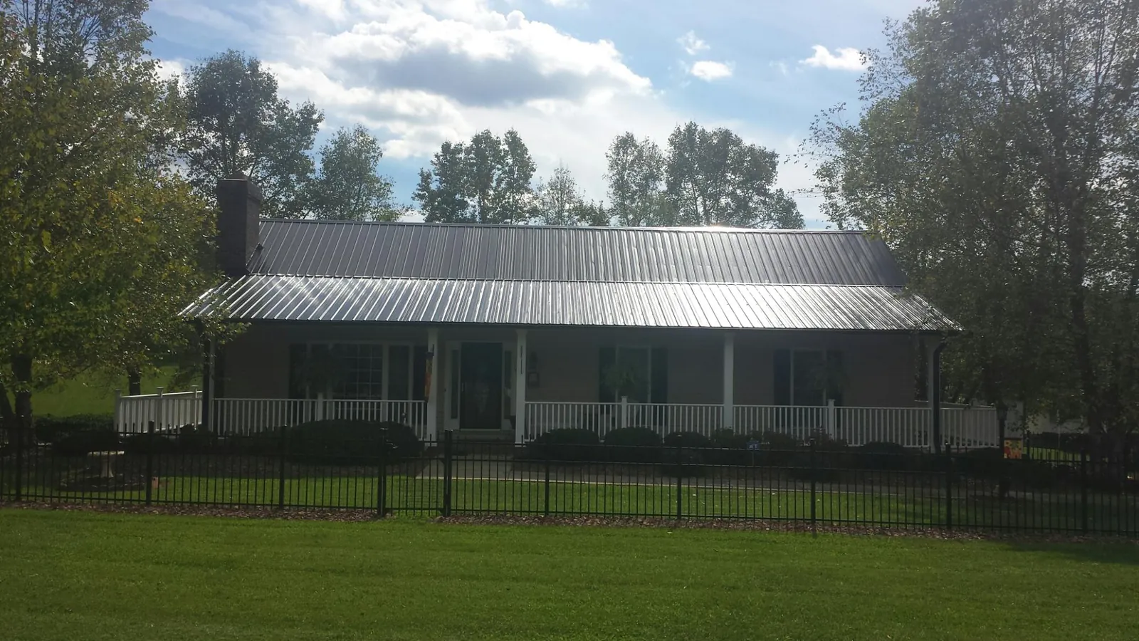 Gray metal roof on a brick ranch with a full width front porch — Gutter Guard Installation work by our crew in Hermitage